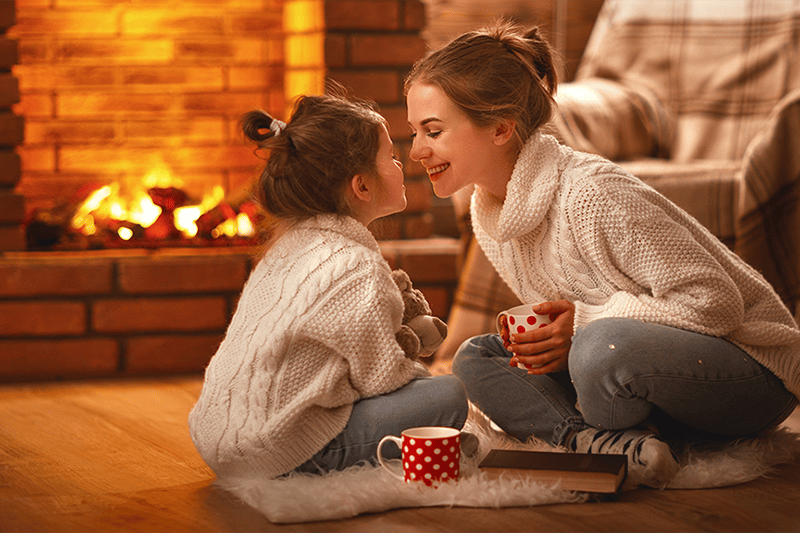 mother and daughter in front of a fireplace.